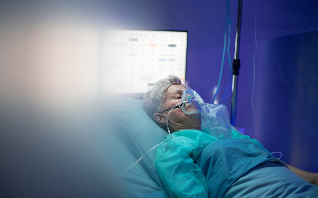 ผู้หญิงนอนใส่เครื่องช่วยหายใจบนเตียงในโรงพยาบาล